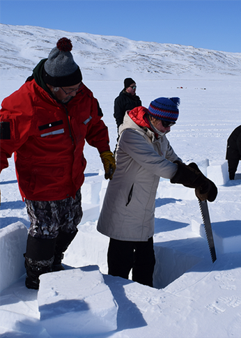 Des personnes sciant des blocs de glace pour construire des igloos